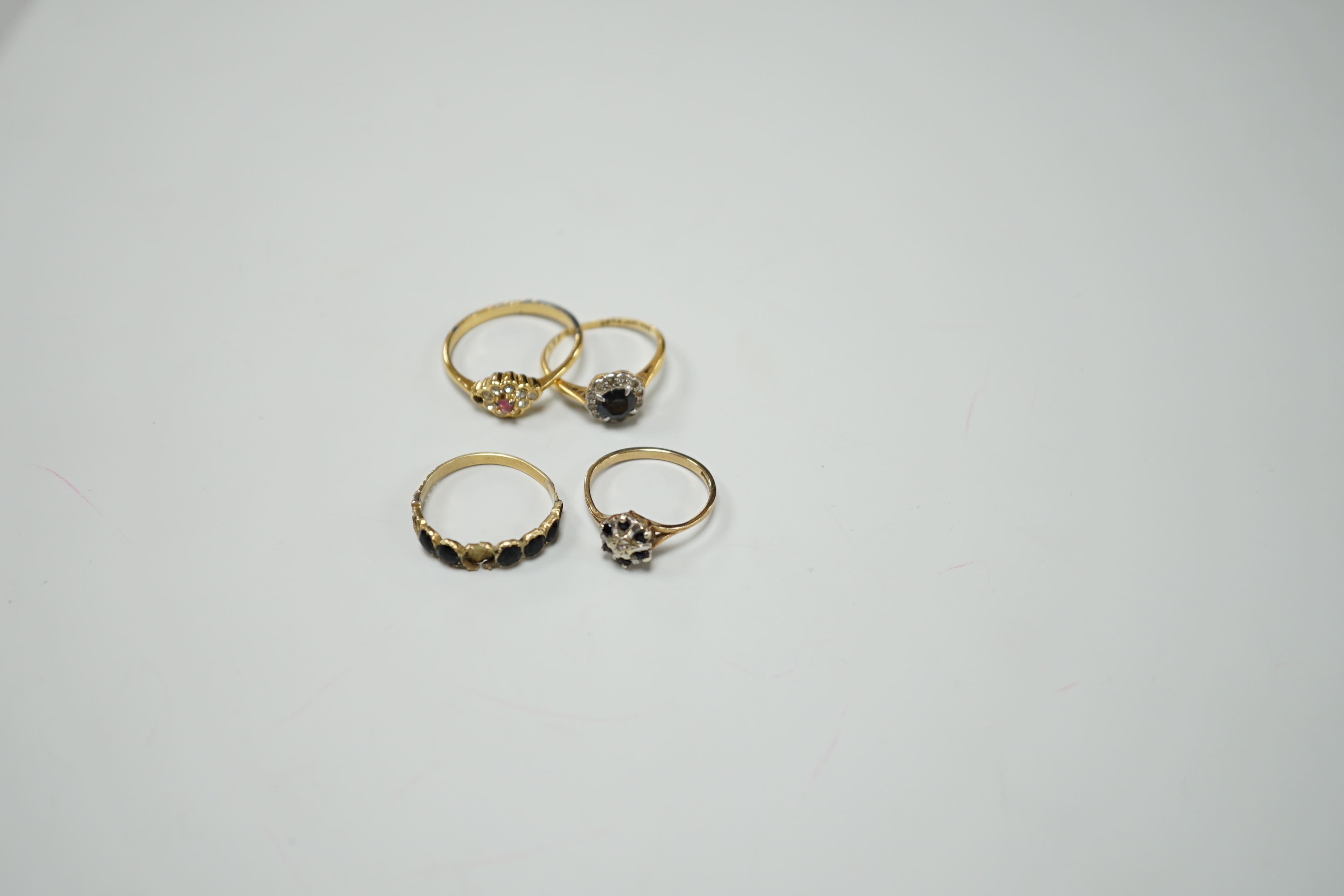 Four assorted diamond and gem set dress rings, comprising an 18ct gold sapphire and diamond cluster, size M, a gilt metal paste lacking one stone, size R, a 9ct gold diamond chip and sapphire, size L and an unmarked jet